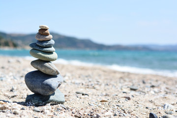 Fototapeta na wymiar Stones pyramid on sand, beach landscape symbolizing zen and balance in life