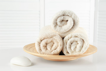 Obraz na płótnie Canvas Plate with soft rolled towels and soap on table
