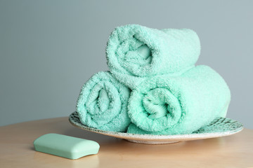 Plate with soft rolled towels and soap  on table