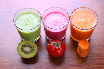 Glasses with fresh juices and ingredients on table