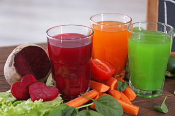 Glasses with fresh juices and ingredients on wooden table