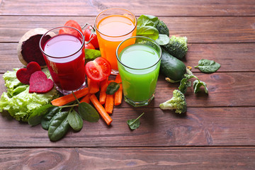 Glasses with fresh juices and ingredients on wooden table