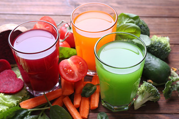 Glasses with fresh juices and ingredients on wooden table