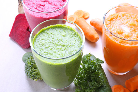 Fresh vegetable juices in glasses and ingredients on table