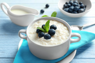 Creamy rice pudding with blueberries on wooden table