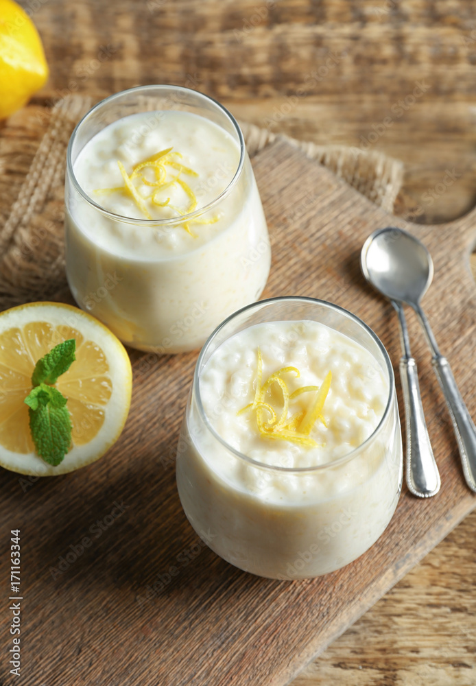 Sticker Creamy rice pudding with lemon in glasses on wooden table