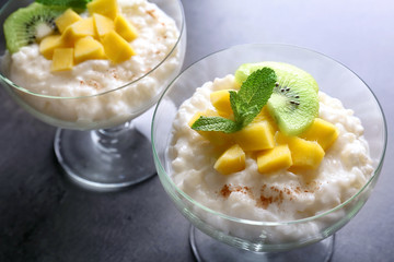 Creamy rice pudding with fruits in dessert bowls on table