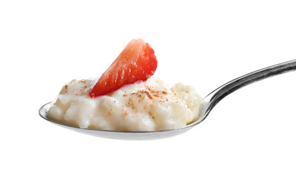 Spoon with creamy rice pudding and strawberry on white background