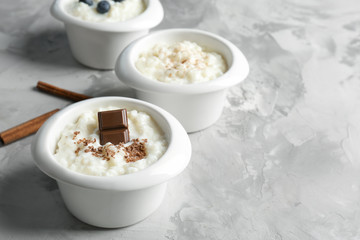 Different creamy rice puddings in bowls on table