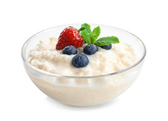 Creamy rice pudding with berries in glass bowl on white background