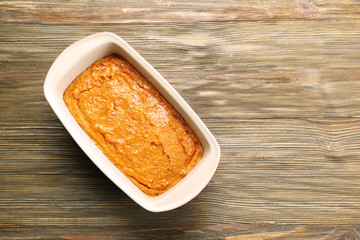 Baking dish with tasty carrot souffle on wooden table