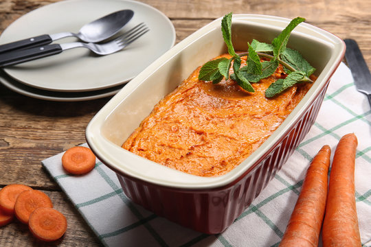Baking dish with tasty carrot souffle on wooden table