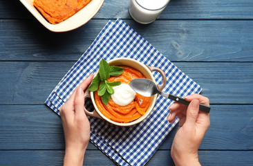 Woman eating tasty carrot souffle at table