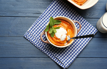Casserole with tasty carrot souffle and spoon on wooden table
