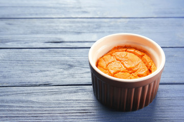 Ramekin with tasty carrot souffle on wooden table