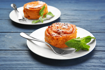 Plates with tasty carrot souffle on wooden table
