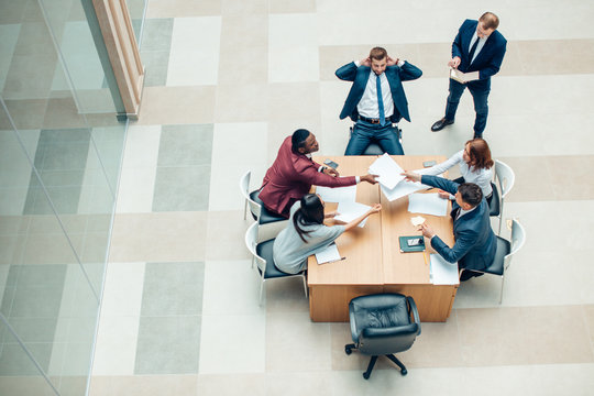 High Angle View Of Businesspeople Discussing In Meeting At Office Desk