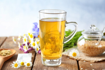 Cup of herbal tea with chamomile flowers on wooden table