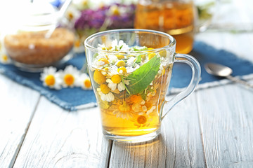 Cup of herbal tea with chamomile flowers on wooden table