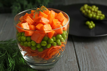 Glass with delicious carrot salad on wooden table