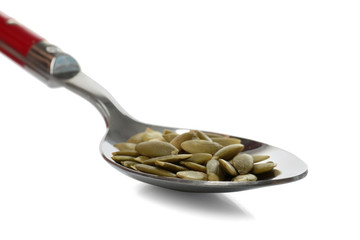 Pumpkin seeds in spoon on white background