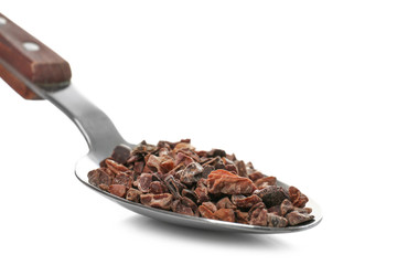 Spoon with cacao nibs on white background