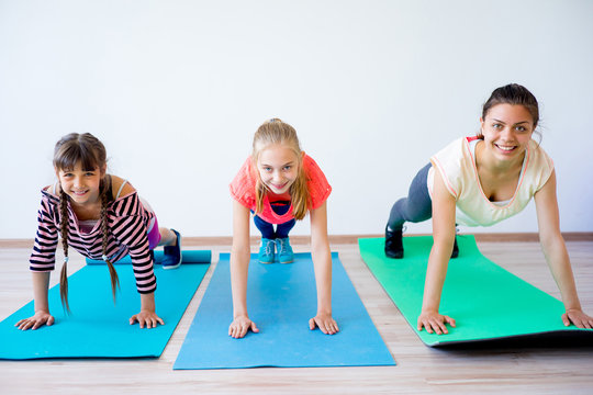 Cute teen girl doing exercises on yoga mat on green grass in