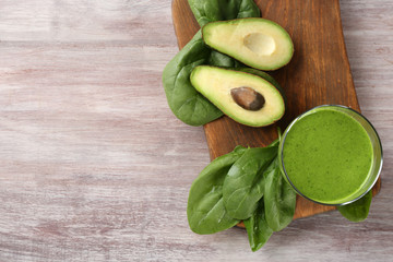 Glass of spinach smoothie on wooden board