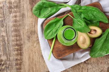 Bottle of spinach smoothie on wooden board