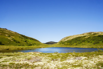 Fototapeta na wymiar Two mountain hills behind a small clean lake