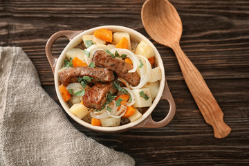 Casserole with tasty meat and potatoes on wooden background