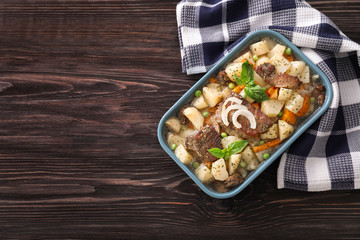 Casserole with tasty meat and potatoes on wooden background