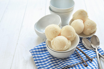 Bowls with delicious vanilla ice-cream balls on table