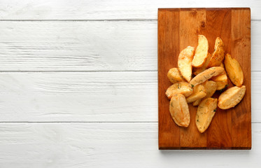 Delicious baked potato wedges on wooden background