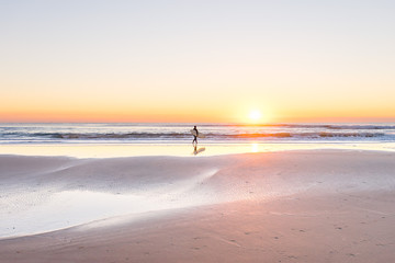 Surfer on the beach at sunrise