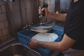Mid section of washing plates at sink