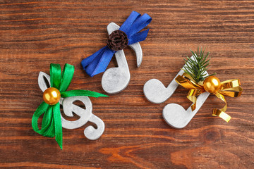 Christmas music concept. Decorative clef and notes with bows on wooden background