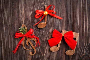 Christmas music concept. Decorative clef and notes with bows on wooden background