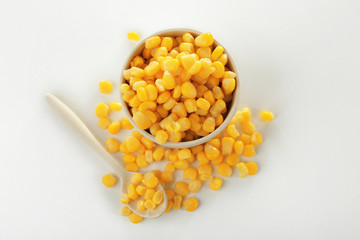 Bowl and canned corn kernels on white background