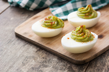 Stuffed eggs with guacamole on wooden table