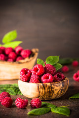 Fresh raspberries in wooden bowl on white table.