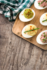 Variety of stuffed eggs with avocado and tuna on wooden table top view
