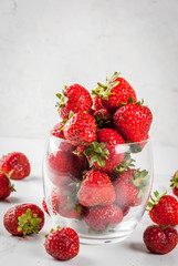 Summer berries and fruit. Fresh raw organic strawberry in drinking glass on white marble table, copy space