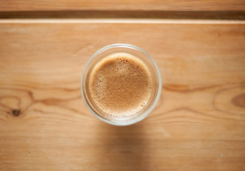 A single shot of espresso in a double wall glass on a wooden table. 