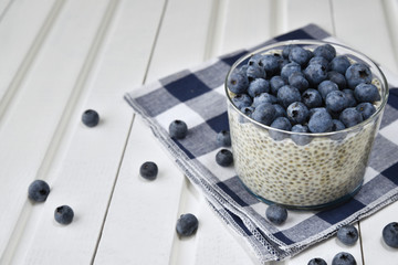 Полезный завтрак: пудинг чиа с черникой на салфетке, белый деревянный фон