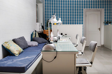 Manicurist workplace in the interior  of beauty salon. Sofas with soft cushions for customers and tables with equipment for manicurists.