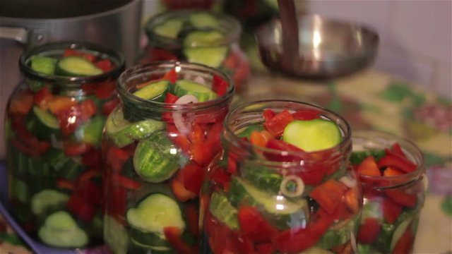 canning salad/A woman puts marinade in cans with cucumbers and pepper