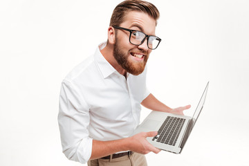 Funny man in eyeglasses holding laptop and staring at camera