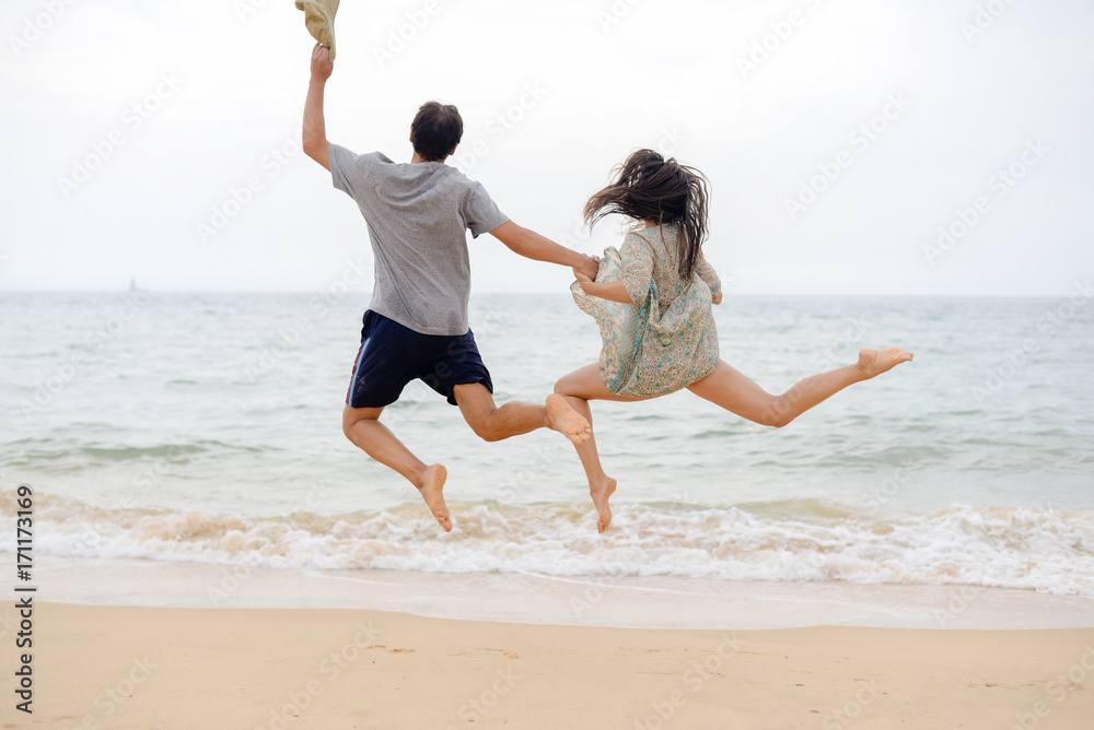 Wall mural lovely couple having fun on the beach outdoors background. back view of healthy people, excitement a