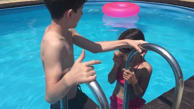 kids bathe in the pool. children boy and girl swimming in the pool playing slow motion video water